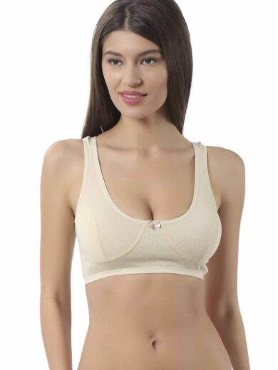 Une femme aux longs cheveux bruns porte la Brassière 100% coton naturel OZ 0564. Elle se tient sur un fond uni blanc, regardant légèrement à sa gauche avec un doux sourire.