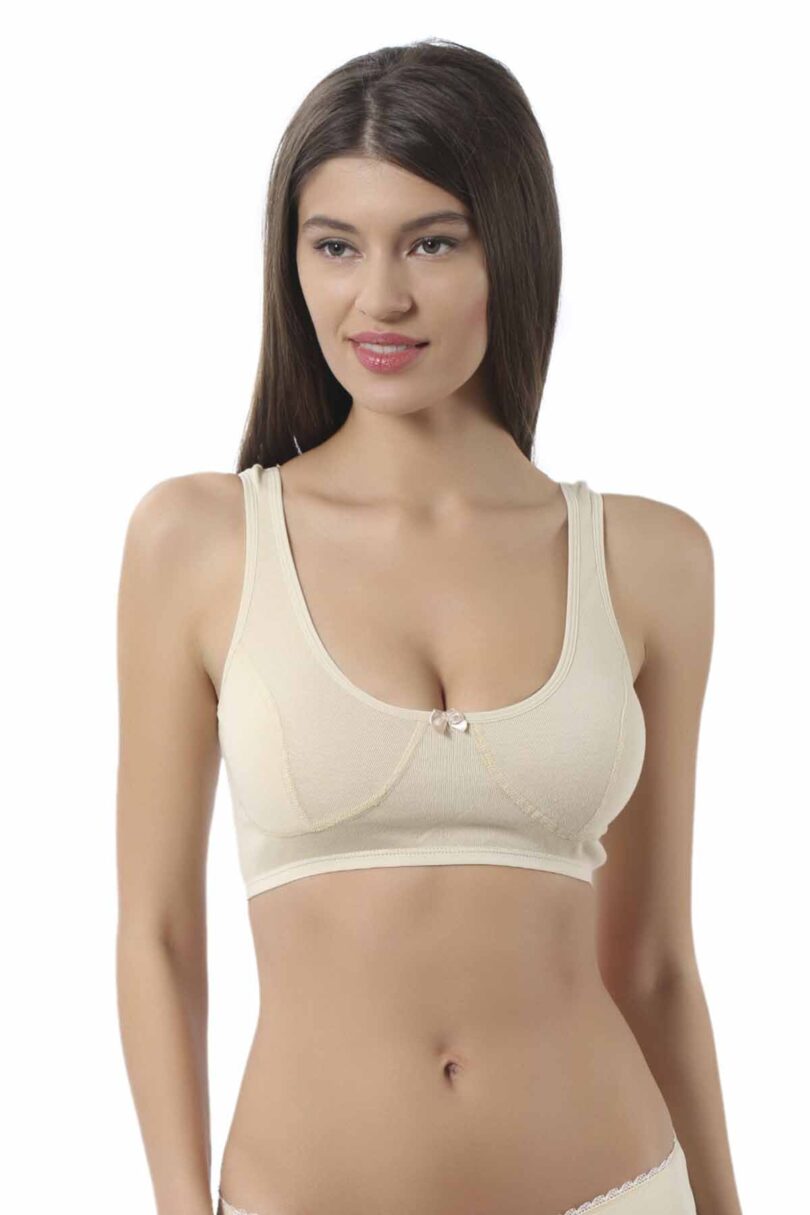 Une femme aux longs cheveux bruns porte la Brassière 100% coton naturel OZ 0564. Elle se tient sur un fond uni blanc, regardant légèrement à sa gauche avec un doux sourire.