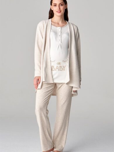Une femme se tient pieds nus dans un ensemble de maternité de couleur claire, plus précisément l'« Ensemble de pyjama post-partum feyza beige ». La tenue comprend un cardigan doux, un haut à manches longues avec le texte « Little Baby » imprimé sur son ventre et un pantalon assorti. Elle dégage une attitude détendue avec ses cheveux lâches.