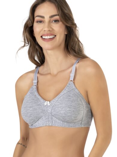 Une femme aux longs cheveux bruns sourit en portant le Soutien-gorge 100 % COTON 351, un soutien-gorge gris clair non rembourré et sans armatures doté de bretelles réglables et d'un petit nœud au centre. Elle a un tatouage visible sur son avant-bras gauche sur un fond blanc uni.
